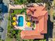 Aerial view of a luxury home with a red tile roof, pool, patios with umbrellas, and landscaped grounds at 1023 Tocobaga Ln, Sarasota, FL 34236