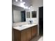 Bright bathroom with double sinks, a large mirror, vanity lighting, and neutral countertops at 15079 Wichita Rd, Port Charlotte, FL 33981