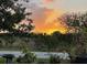 Scenic view of a gorgeous sunset beyond mature trees and native landscaping at 15079 Wichita Rd, Port Charlotte, FL 33981