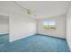 A sunny bedroom with blue carpet, ceiling fan, and a window with an ocean view at 250 Santa Maria St # 120, Venice, FL 34285