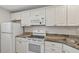 A bright kitchen with white cabinets, updated appliances, and granite countertops at 250 Santa Maria St # 120, Venice, FL 34285