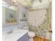 Well-lit bathroom featuring a shower with floral curtains, a vanity, and a light blue painted wall at 3500 El Conquistador Pkwy # 119, Bradenton, FL 34210