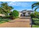 Beautiful home showcasing a brick driveway, manicured lawn, and lush tropical landscaping at 5341 Greenbrook Dr, Sarasota, FL 34238