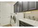 Well-equipped laundry room with modern washer, dryer, and dark cabinets at 5341 Greenbrook Dr, Sarasota, FL 34238