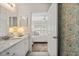 Bathroom view through the bedroom doorway with floral wallpaper and granite vanity at 5711 Soldier Cir # 204, Sarasota, FL 34233