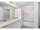 Well-lit bathroom with white cabinets, granite countertops, and a bathtub with tiled backsplash at 5711 Soldier Cir # 204, Sarasota, FL 34233