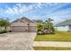 Inviting home featuring a three-car garage, manicured lawn, landscaped beds, and a brick paved driveway at 6428 Devesta Loop, Palmetto, FL 34221