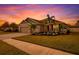 Beautiful single-story home with a well-manicured lawn, palm trees, and a paver driveway set against a colorful sunset at 6428 Devesta Loop, Palmetto, FL 34221