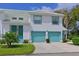 Bright two-story townhome with a two-car garage and turquoise accents, landscaped with green grass, shrubbery, and small trees at 6589 Fairway Gardens Dr # 202, Bradenton, FL 34203