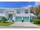 Bright two-story townhome with a two-car garage and turquoise accents, landscaped with green grass, shrubbery, and small trees at 6589 Fairway Gardens Dr # 202, Bradenton, FL 34203