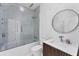 Modern bathroom with a glass enclosed shower/tub combination and a round mirror over the vanity at 6669 Windjammer Pl, Lakewood Ranch, FL 34202