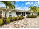 Charming home exterior with lush landscaping, a tiled patio, and mature palm trees at 121 Holly Ave, Sarasota, FL 34243