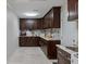 A butler's pantry with stone countertops, dark brown cabinets and tiled floors creates a space for preparation at 121 Holly Ave, Sarasota, FL 34243