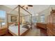 Comfortable main bedroom featuring a four-poster bed, hardwood floors, and ample natural light at 12471 Natureview Cir, Bradenton, FL 34212