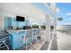 An outdoor bar area features a grill, tv, countertop and seating, with views of the water and swimming pool at 12917 42Nd W Ter, Cortez, FL 34215