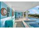 A poolside patio offers a table and chairs, a swim spa, and art accents in a covered and comfortable space at 12917 42Nd W Ter, Cortez, FL 34215