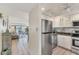 Modern kitchen open to the living area with stainless steel fridge and white cabinets at 4350 Chatham Dr # E106, Longboat Key, FL 34228