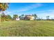 Wide shot of backyard featuring the home, green lawn, and surrounding trees on a clear day at 8059 Strasse Blvd, Punta Gorda, FL 33982