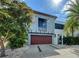 Contemporary two-story house with a wooden garage door, balcony, sleek design, and well-maintained yard at 2434 Wood St, Sarasota, FL 34237
