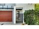 Close-up of the modern home's front gate with a sleek design and lush landscaping and a wood-toned garage at 2434 Wood St, Sarasota, FL 34237