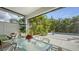 Relaxing screened-in patio with dining set and view of the lush landscaped backyard and sparkling pool at 2434 Wood St, Sarasota, FL 34237
