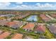 Aerial view of a residential area featuring a community lake surrounded by homes with tile roofs and green lawns at 5116 Tivoli Run, Bradenton, FL 34211
