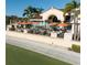 Clubhouse exterior with outdoor seating featuring orange umbrellas and surrounding green landscape at 7460 Monte Verde, Sarasota, FL 34238