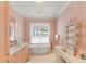 Elegant bathroom with a freestanding tub, marble floors, and pink patterned wallpaper at 8501 Midnight Pass Rd, Sarasota, FL 34242
