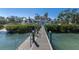 Waterfront home featuring a private dock, lush landscaping, and beautiful facade at 8501 Midnight Pass Rd, Sarasota, FL 34242