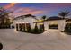 Luxury white estate with dark wood garage doors and porte cochere entrance at sunset at 8501 Midnight Pass Rd, Sarasota, FL 34242