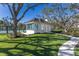 Charming white building with blue shutters nestled among mature trees, and lush green lawn at 8501 Midnight Pass Rd, Sarasota, FL 34242