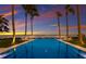 A stunning backyard pool reflecting the sunset sky, framed by tall palm trees and well-manicured landscaping at 8501 Midnight Pass Rd, Sarasota, FL 34242
