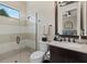 Bright bathroom featuring shower with glass door, dark wood vanity, sink, and large mirror at 15608 Leven Links Pl, Lakewood Ranch, FL 34202