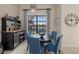 Cozy dining area with blue chairs, bar area, modern light fixture, and a view of the lake at 15608 Leven Links Pl, Lakewood Ranch, FL 34202