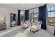 Bright sitting room with comfortable chairs, dark blue curtains, and a large window overlooking the water at 15608 Leven Links Pl, Lakewood Ranch, FL 34202