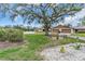 Home exterior featuring a large tree, lush grass, and a cozy seating area with benches at 1817 Curry Ave # 57, Nokomis, FL 34275