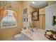 Bright bathroom with a white vanity, decorative mirror, and window with colorful valance at 5521 Bilbao Pl, Sarasota, FL 34238