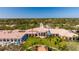 Exterior shot of the clubhouse, featuring manicured lawns, palm trees, and a clock tower against a clear blue sky at 5521 Bilbao Pl, Sarasota, FL 34238