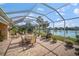 Spacious screened patio with brick flooring, dining area, and scenic waterfront views at 5521 Bilbao Pl, Sarasota, FL 34238