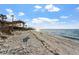 Serene beach view with sandy shore and calm ocean waters under a clear blue sky with scattered clouds at 11 Sunset Dr # 406, Sarasota, FL 34236
