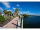 Beautiful waterfront view featuring a brick walkway, palm trees, and the blue ocean in Florida at 26720 Weiskopf Dr, Englewood, FL 34223