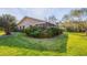Well-maintained backyard with green lawn, lush shrubbery, and partial view of the home's exterior at 3443 Tallywood Cir # 7061, Sarasota, FL 34237