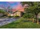 Charming single-story home with a well-manicured lawn and mature trees under a colorful sky at sunset at 3443 Tallywood Cir # 7061, Sarasota, FL 34237