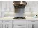 Close up of a stylish stove with a stainless steel range hood and white cabinets at 4745 Benito Ct, Lakewood Ranch, FL 34211