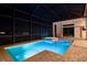 Illuminated pool and spa at night in an enclosed patio with brick pavers and views of the water in the distance at 4745 Benito Ct, Lakewood Ranch, FL 34211