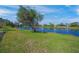 Beautiful backyard featuring a serene lake view, lush green grass, and mature trees at 531 Latitude Ln, Osprey, FL 34229
