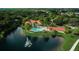 Stunning aerial view of the community pool surrounded by lush greenery and a serene lake with a fountain at 557 Marsh Creek Rd, Venice, FL 34292