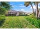 Spacious backyard with lush green grass and mature trees, screened lanai visible with neutral exterior at 557 Marsh Creek Rd, Venice, FL 34292