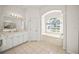 Bright bathroom features double vanity, soaking tub under an arched window, and tile flooring at 557 Marsh Creek Rd, Venice, FL 34292