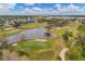 Aerial view of a golf course with ponds, sand traps, fairways, and surrounding neighborhood at 9214 Raes Creek Pl, Palmetto, FL 34221